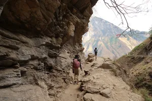 Hikers trek along a narrow rocky path on the High Trail of Tiger Leaping Gorge in Lijiang