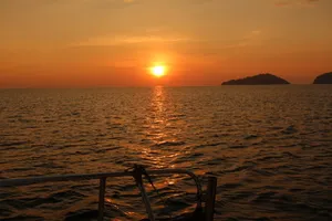 Matahari terbenam di atas laut yang tenang dengan rel kapal layar di latar depan semasa pelayaran matahari terbenam peribadi dari Kota Kinabalu, Sabah