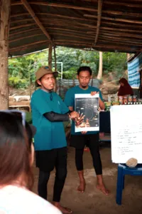 Rinca Coral Nursery Program hosts presenting coral restoration notes to participants under a rustic shelter on Komodo Island