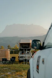 Borneo Overland wild roadtrip campsite near Kota Kinabalu with vans parked and hazy Mt Kinabalu in the distance