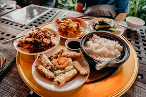 会安美食之旅的餐食摆放在编织桌面上:白盘里有一碗米饭、炸开胃小食和炒菜