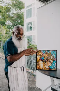 Glass artist at Singapore’s Art Glass Centre standing by a stained-glass panel in an outdoor studio area — workshops in Singapore