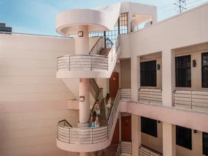 Two travellers moving up a spiral staircase inside a white heritage building in Katong-Joo Chiat, Singapore, to uncover Singapore hidden gems