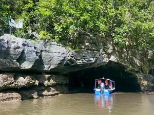 Small boat passing under limestone cliffs in Langkawi’s Tanjung Rhu UNESCO Geopark on a naturalist-guided cruise