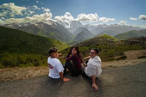 Travellers pausing on a gravel shoulder with sweeping valley hills and snow-dusted peaks during the 6-day Shangri-La Loop