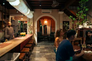 酒保在温暖的砖墙酒吧角落调制饮品，客人们一边享受会安鸡尾酒之旅