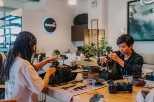 Participants shaping tropical bonsai at a Singapore workshop, hands working over potted trees at a shared bench — workshops in Singapore