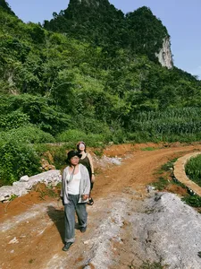 Travellers posing on a rocky roadside viewpoint with jungle hills behind during a 3D3N motorbike loop in Cao Bang