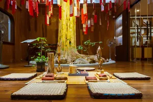 Agarwood exhibition room in Hanoi with carved wood specimens on floor mats beneath hung Vietnamese banners