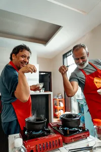 在会安 Jolie Cooking Class 的越南家常烹饪体验中，两位系着红围裙的人正在炉边搅拌锅里的食材
