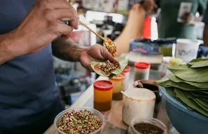 Tangan menyajikan hidangan pembuka ke piring beralas daun di atas meja, dari Hidden Heritage dalam pengalaman hidden gems Secrets of the Streets di Singapura