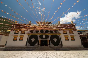 Tibetan prayer flags strung above a monastery courtyard in Shangri-La, with ornate walls under blue sky
