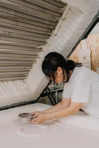 Tan Sock Fong pours and shapes materials for a glass centrepiece near the kiln wall in Singapore, workshops in Singapore