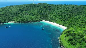 Aerial view of Lombok’s Pink Beach cove with clear turquoise water and small dive boats, on a Scuba Froggy fun dive trip