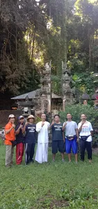 Group portrait outdoors at Omunity Bali in Bali, standing by Balinese stone shrines and greenery during a sacred cleansing retreat
