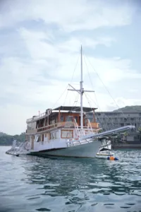Wooden liveaboard sailing boat with rigging moored on calm water for a 3D2N join-in Komodo trip in Labuan Bajo
