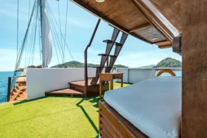 Private 3D2N Komodo cruise on a sleek white phinisi: outdoor deck cabin with neatly made double bed in Labuan Bajo