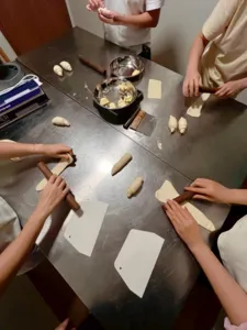 Hands portioning shio pan dough at a The Daily Staples workshop in Singapore, with floury pieces, trays and rolling tools on the bench