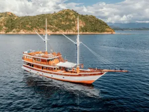Wooden phinisi cruising near forested islands off Labuan Bajo during a 4D3N shared Komodo cruise, Labuan Bajo