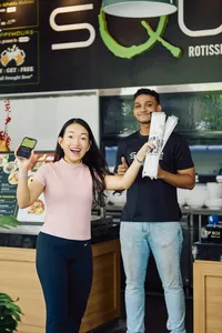 在新加坡河畔一家餐厅柜台参与现实版大富翁游戏的客人,手拿代金券和菜单——新加坡小众宝藏