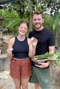 Kebun Lidstari hosts smiling outdoors in Langkawi, holding green leaves and a basket of herbs from the garden