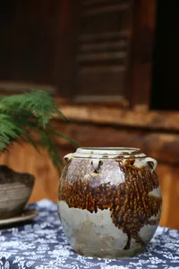 Glazed ceramic storage jar on a patterned cloth inside a traditional wooden room at an ancient pottery village visit in Shangri-La