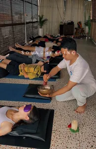 Quiet sound-healing session in a studio in Canggu, with participants lying on mats as a host plays a singing bowl