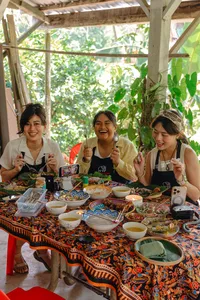 Guests enjoying an Indigenous Sabahan cooking meal in Kota Kinabalu, seated under a wooden shelter with shared dishes