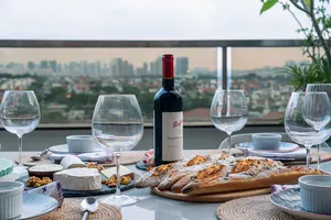 Loft dining table with sliced baguettes, wine bottles, and glasses against Singapore city views—private dining Singapore