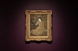 Gold-framed portrait painting hanging on a purple wall in Quang San Art Museum, Ho Chi Minh City exhibition hall