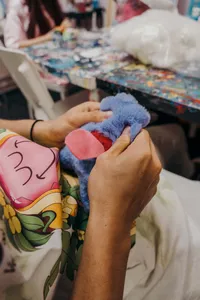 Close-up of hands stuffing a blue plush piece and attaching it to create an ugly-cute keychain in Singapore