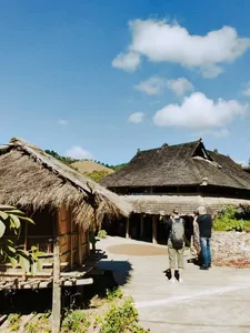 Wisatawan berjalan melewati rumah beratap jerami khas Dai di jalur halaman terbuka saat perjalanan sehari privat di Xishuangbanna