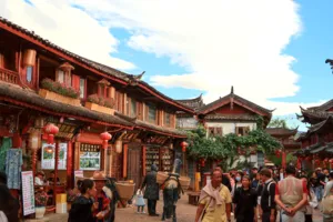 Lijiang Old Town street scene with red lanterns, bronze statue figures and bustling travellers browsing shops during a local-guided walk