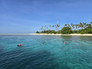 Snorkel day on Semporna’s islands: red kayaks near a palm-lined sandbar above clear turquoise water, with Bigfin Divers