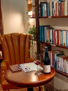 Cozy table set for a wine tasting at Chan Dat Living Room in Hoi An, with a glass, bottle, and nearby bookshelves
