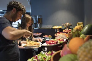Guests enjoying a buffet on a party cruise, with fruit and appetisers arranged on serving stations in Halong Bay
