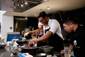 Cooking at saucepans in Singapore during the team local produce cooking challenge, chefs guide diners — workshops in Singapore