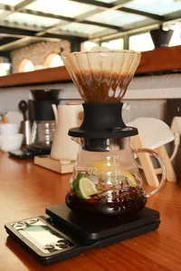 Carafe of brewed coffee with a pour-over dripper and a tasting card on the counter in a Lijiang specialty coffee workshop