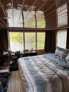 Air-conditioned houseboat cabin interior with a large bed and open window overlooking the river in Tanjung Puting