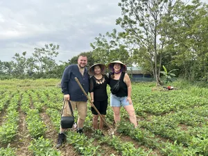 Travellers planting young rice in a muddy paddy at Duong Lam ancient village near Hanoi, led through a hands-on routine