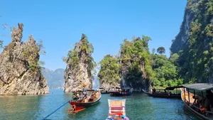 Multiple long-tail boats moored along steep cliffs while travellers prepare to continue the journey at Cheow Lan Lake