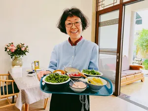 Fancy serving Yunnan dishes at a dining table in Lijiang during a market-to-table cooking experience, with bowls of greens