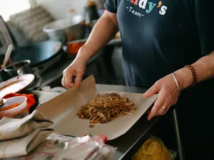 Hands spreading a mound of shredded noodles onto parchment during the Joo Chiat food tour, Singapore hidden gems