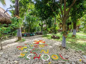 Colourful flower mandala offerings arranged on a stone courtyard among tropical trees at Omunity Bali in Bali