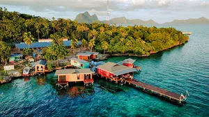 Aerial view of Luma Selakan sea lodge complex in Semporna with wooden platforms, boatsheds and jetty over the lagoon