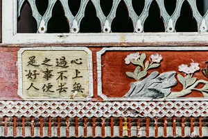 Close-up pintu masuk halaman rumah kaum Bai dengan panel ukiran hiasan dan kaligrafi Cina di pekan lama Xizhou, Dali