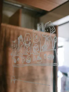 Line-drawn characters on a frosted glass panel inside a Singapore shop in Joo Chiat during a food tour
