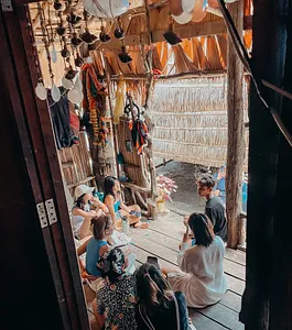 Group dining and chatting inside a thatched Moken-style hut during a Surin Island beach camping stay near Khao Lak