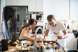 French Cooking Lab chef guiding croissant dough shaping at the counter in a bright Singapore kitchen baking class