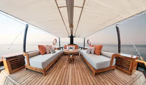 Sun deck with cushioned daybeds and a central table on a private 3D2N Komodo liveaboard, cruising near Labuan Bajo
